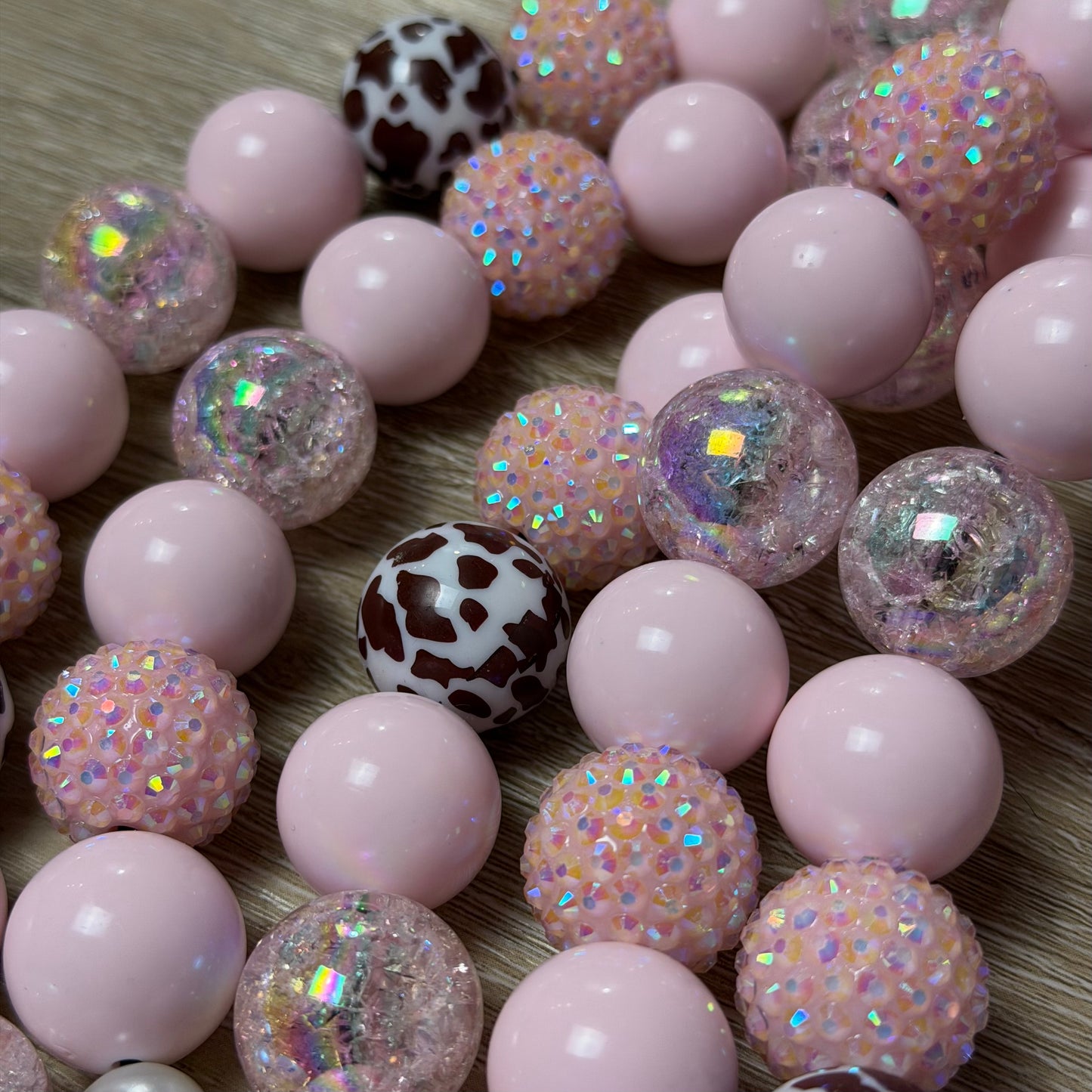 Close up of POPNCO handcrafted beaded pet collars Jolene laying flat on a white background featuring pale pink solid, crackle and rhinestone bayberries mixed with brown cow print beads. 