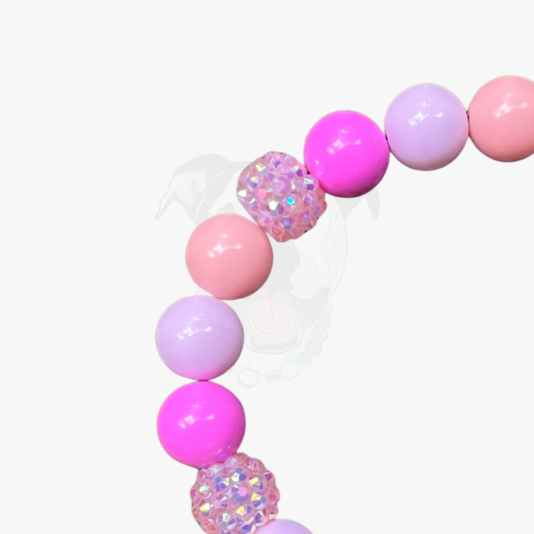 Decorative balloon arch with pink, purple, and iridescent balloons on a white background