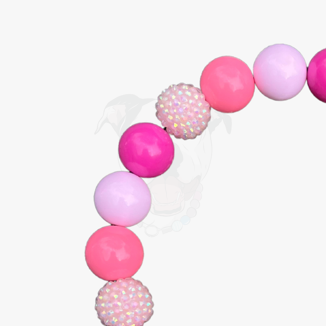 Pink and purple balloon garland with glittery accents on a white background