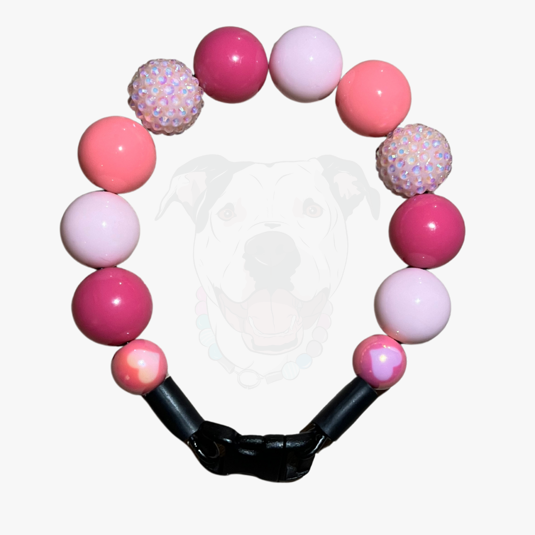 Pink and white beaded bracelet with a black clasp on a white background