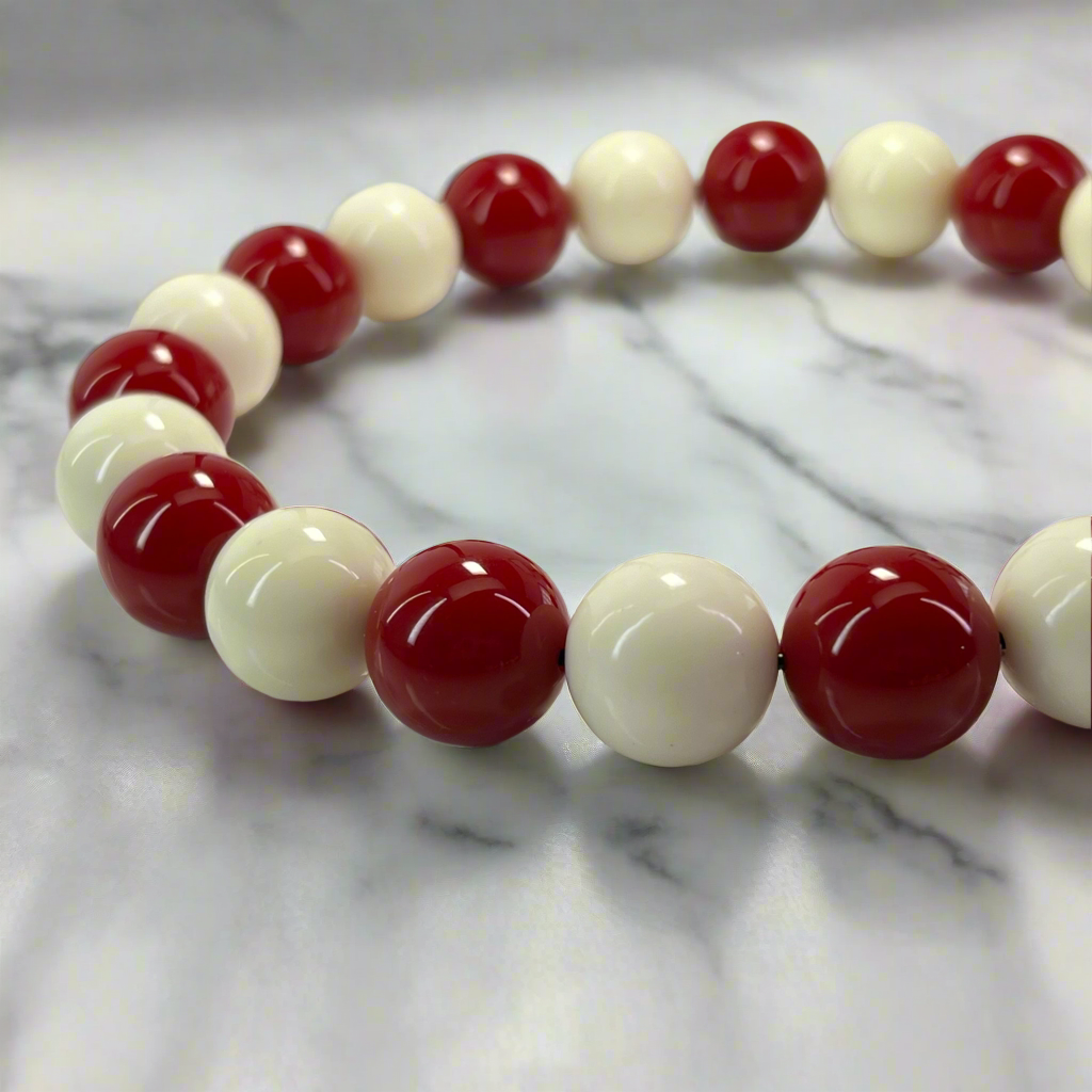 Beaded bracelet with red and white beads on a marble surface