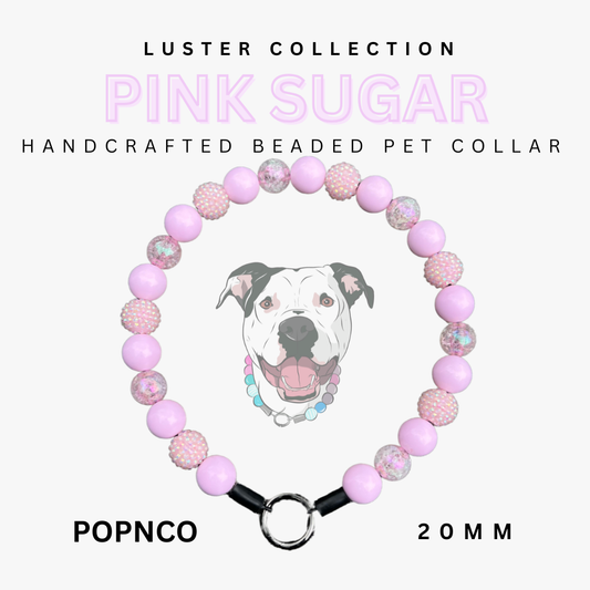 Handcrafted beaded pet collar with pink and white beads, featuring a dog illustration, on a white background. Brand 'Luster Collection' and product name 'Pink Sugar' are displayed.