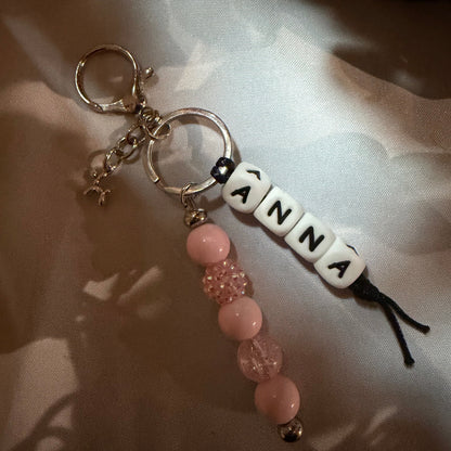 Keychain with 'ANNA' beads on a light fabric background POPNCO