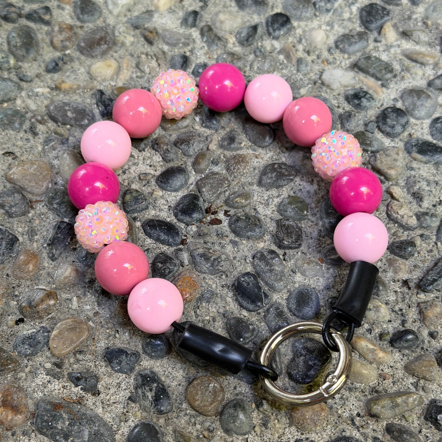 Popnco Penelopes pale pink, rose pink and bright pink solid acrylic beads mixed with light pink resin rhinestone bayberry beads as a Beaded Pet Collar Laying Flat on Rocky surface 