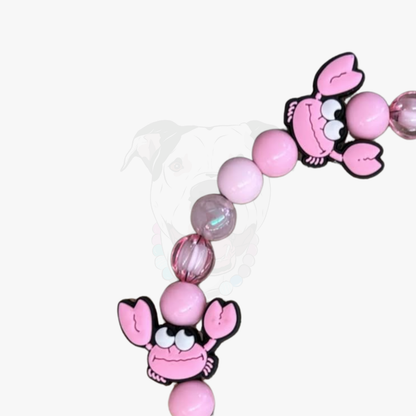 Pink beaded bracelet with cartoon lobster charms on a white background