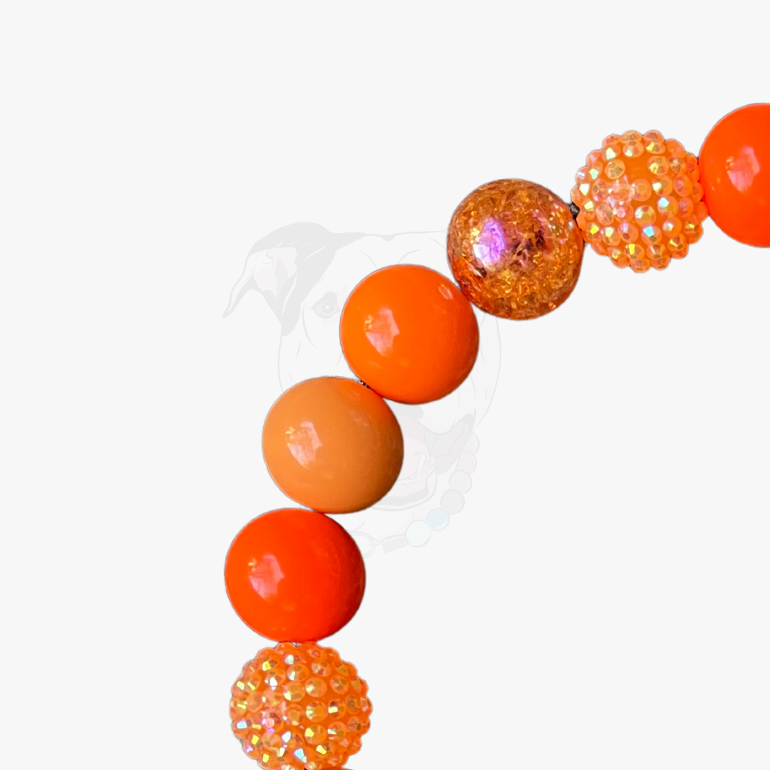 Necklace with orange and glittery beads on a white background