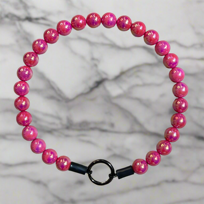 Pink beaded bracelet with a black clasp on a marble background
