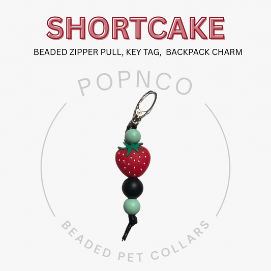 Beaded zipper pull, key tag, or backpack charm with strawberry design on a white background, featuring the brand 'Popnco'.