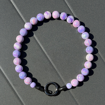 Purple beaded dog collar with a black clasp on a gray surface from POPNCO