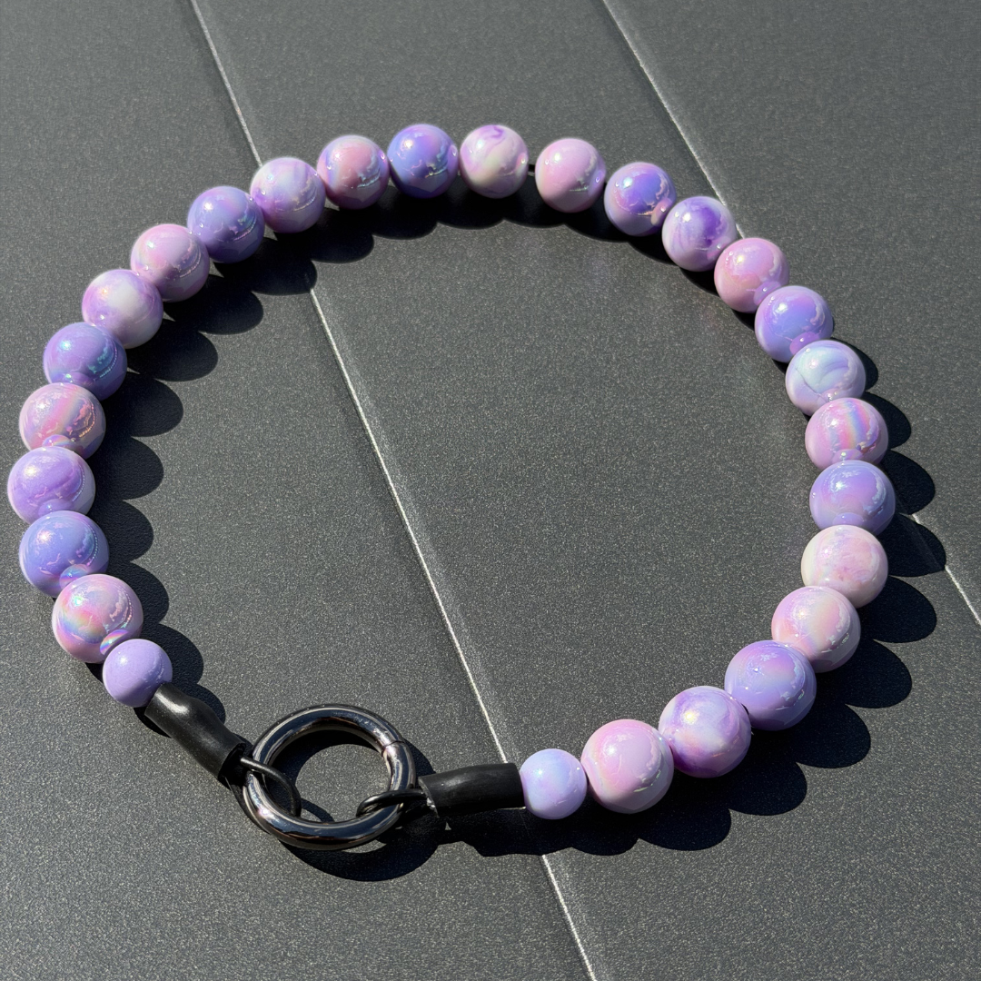 Purple beaded dog collar with a black clasp on a gray surface from POPNCO