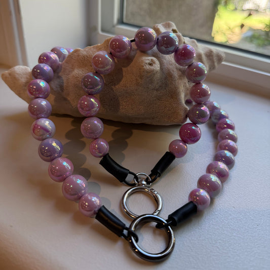 Beaded necklace with black clasp on a light surface near a window