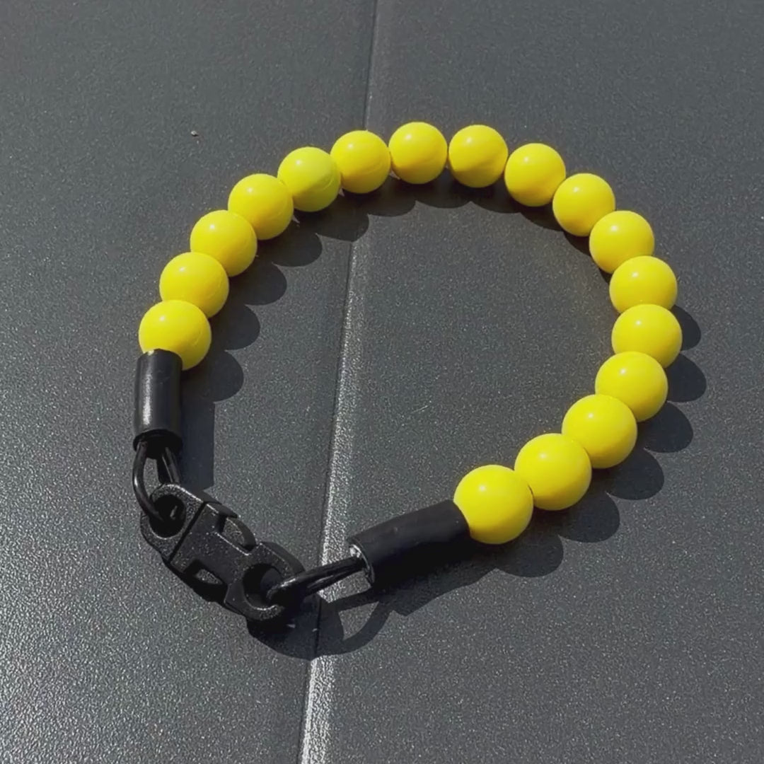 Close up Video of the Popnco collar laying on a black table. It is a Classic Solid beaded pet Collar from POPNCO Called Sunny, featuring Solid warm 12mm Acrylic yellow beads.