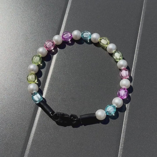 Video of Rainbow Theme Beaded pet Collar from POPNCO featuring 12mm beads alternating Blue, yellow, green, pink, purple faceted beads alternating with acrylic pearls laying flat on a black table. 