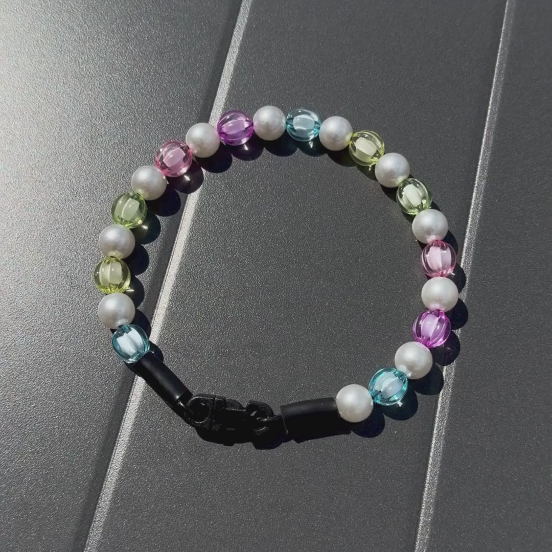 Video of Rainbow Theme Beaded pet Collar from POPNCO featuring 12mm beads alternating Blue, yellow, green, pink, purple faceted beads alternating with acrylic pearls laying flat on a black table. 